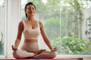 Woman meditating by window, representing feminine flow and empowerment 